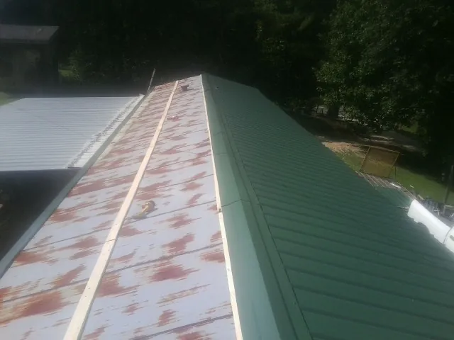 Old rusted panels beside newly installed green metal roofing — Wind Damage Roof Repair by Roofing Brothers in Watkinsville