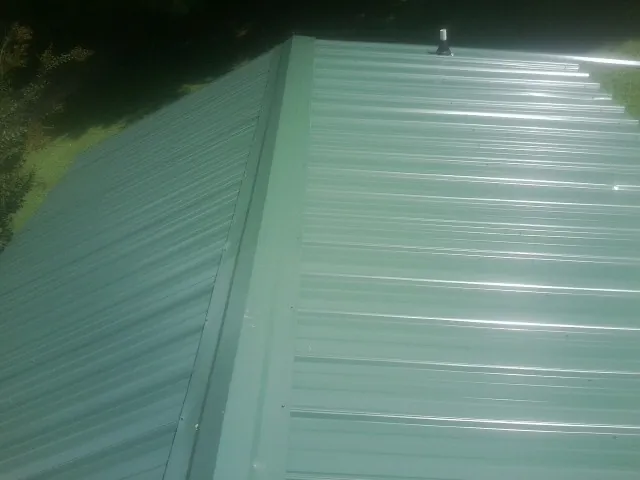 New green metal panels meeting at the ridge of a roof — Flat Roof Repair work by our crew in Watkinsville