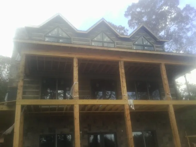 Dormers and porch framing on a large log home under construction — Roof Coating work by our crew in Watkinsville