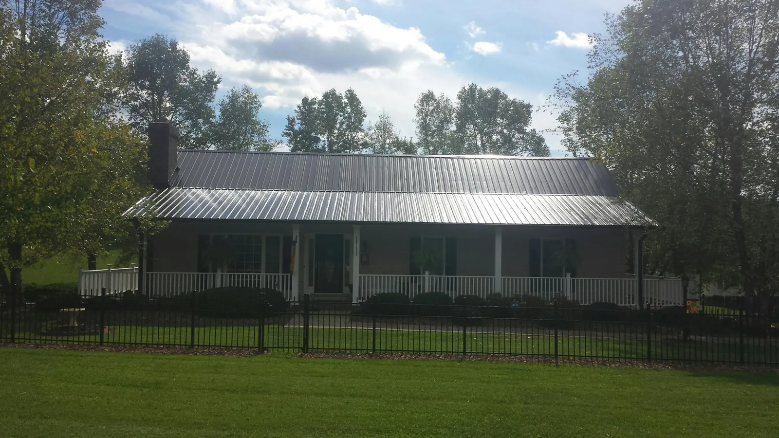 Gray metal roof on a brick ranch with a full width front porch — Gutter Guard Installation work by our crew in Watkinsville