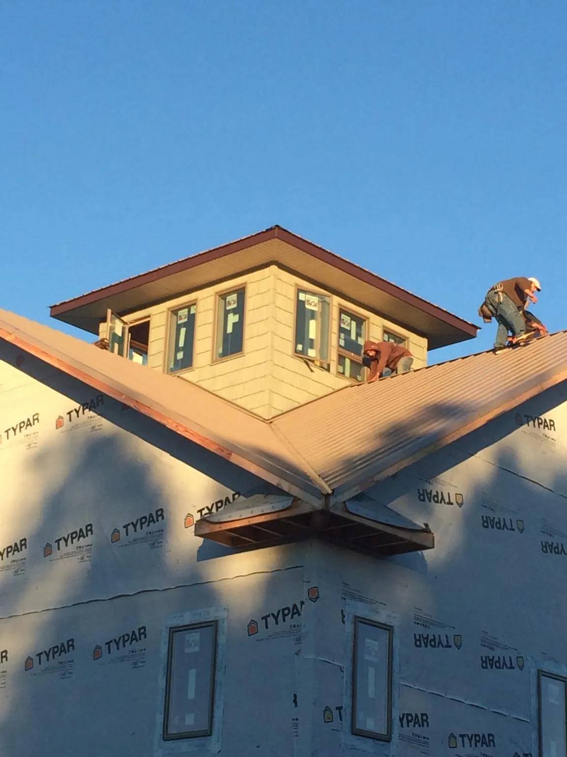 Roofers working around a rooftop cupola on a new metal roof at sunset — Roof Waterproofing in Watkinsville by Roofing Brothers